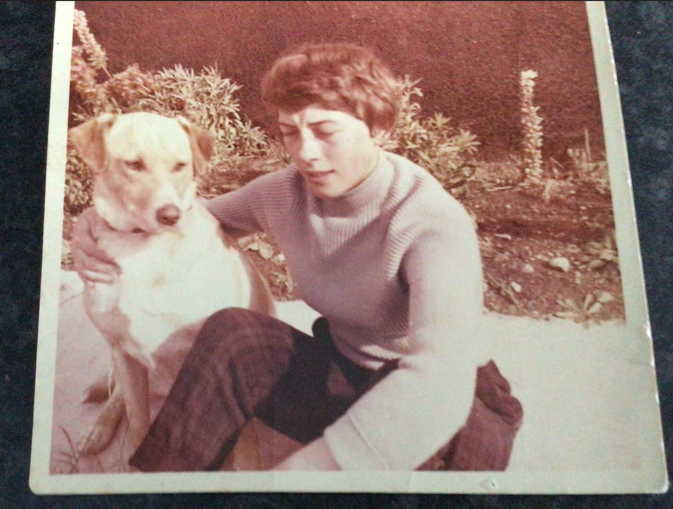 Young Edna Clyne-Rekhy seated outdoors beside her Labrador Retriever, Major